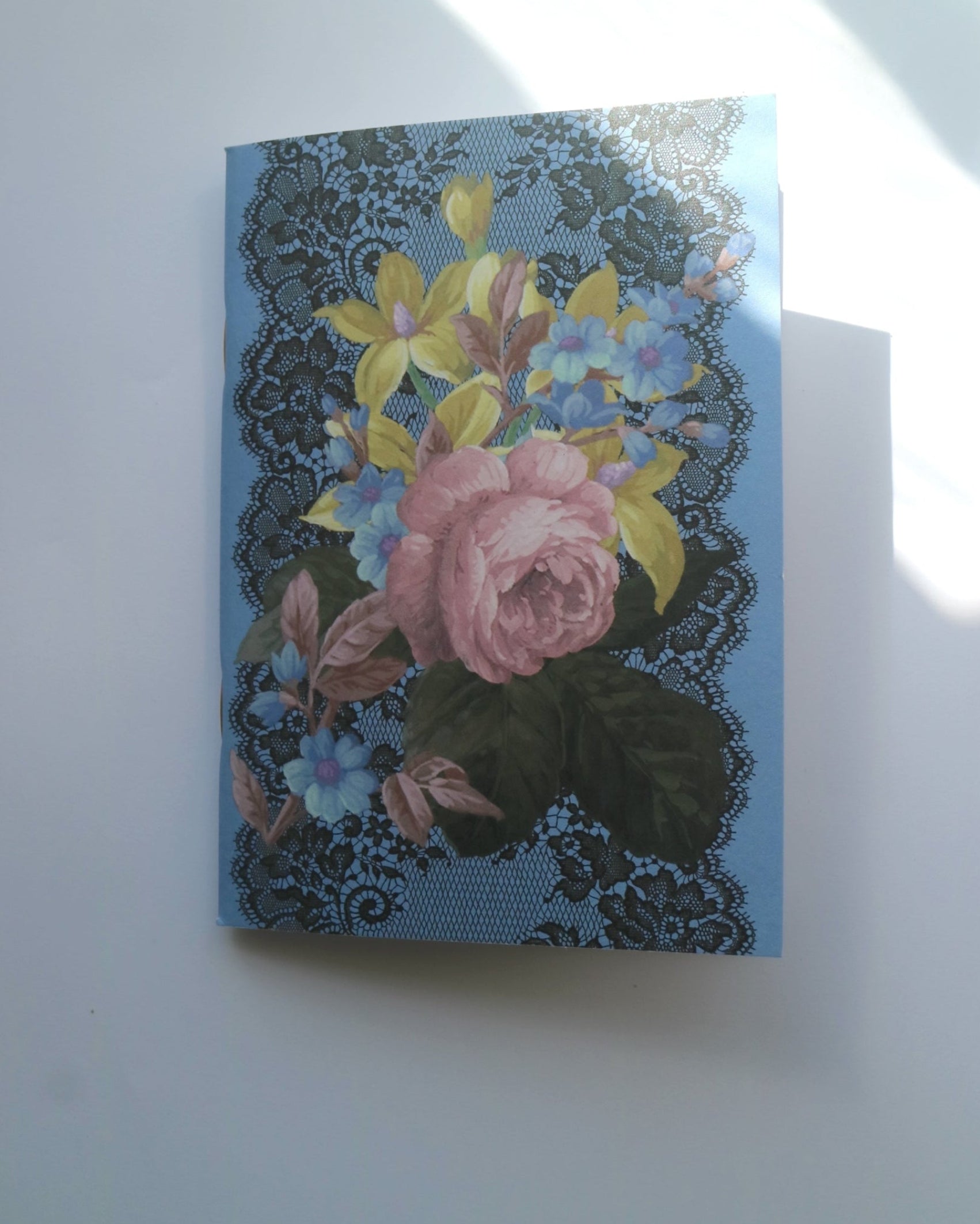 Decorative notebook with floral andl black lace design on a blue background